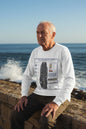 A white long-sleeve crewneck t-shirt featuring a detailed graphic print of the USS Enterprise (CVN-85) aircraft carrier deck and surrounding military insignia on the front.